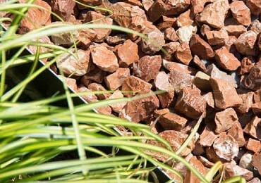 Un jardín mediterráneo con gravilla roja